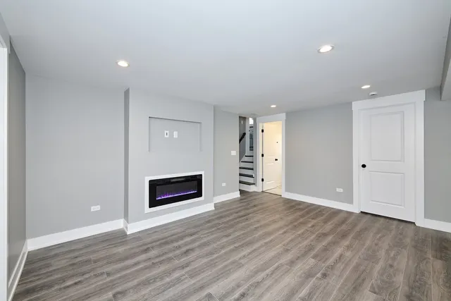 a view of an empty room with wooden floor fireplace and a window