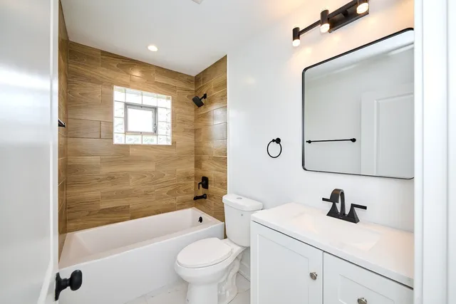 a bathroom with a bathtub shower sink mirror and toilet