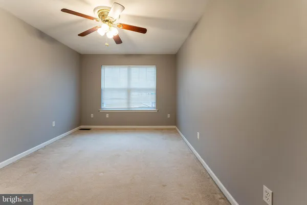 an empty room with a window and a fan