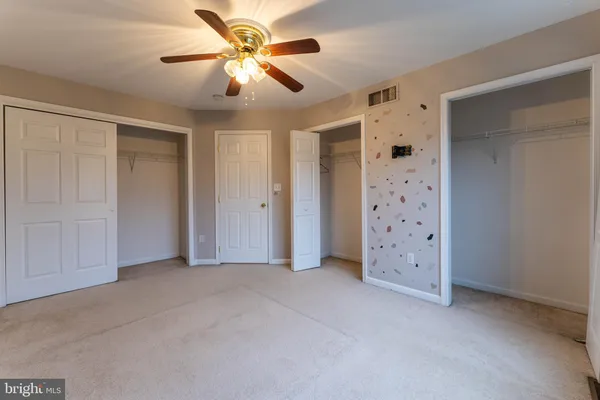 an empty room with closet and a chandelier fan