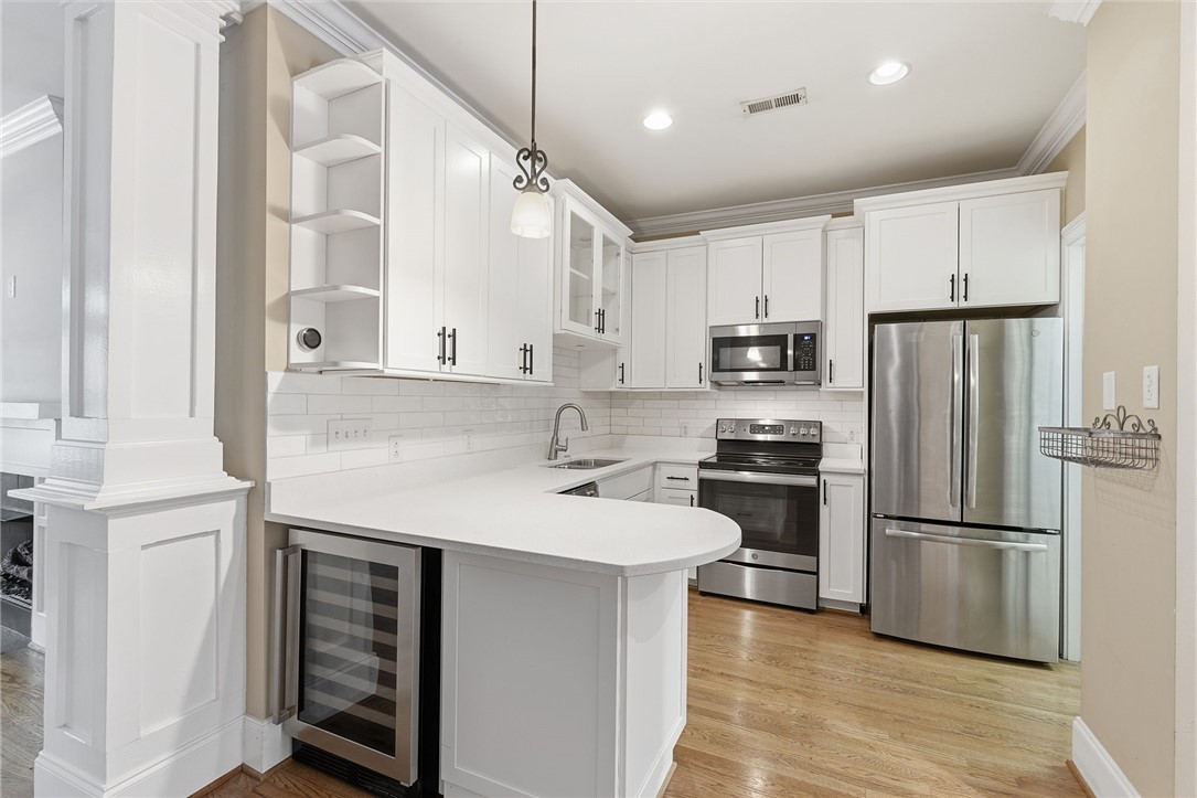 204 Butler Avenue Greenville, SC 29601 - Photo 11 of 26 White cabinetry and subway tile backsplash complement stainless steel appliances in this functional kitchen.