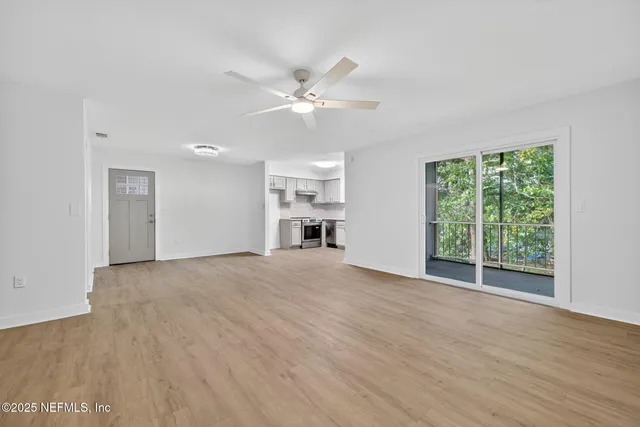 a view of empty room with wooden floor and fan