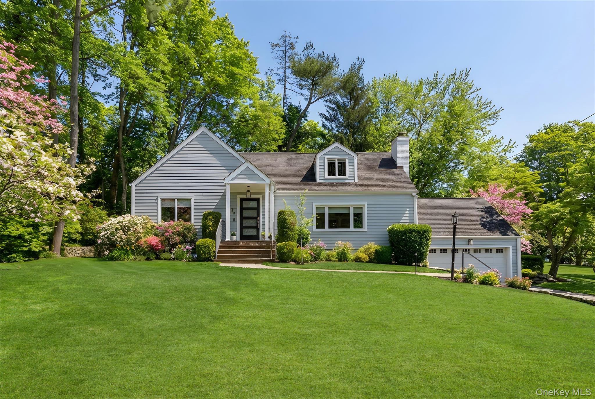 a front view of a house with a garden and trees