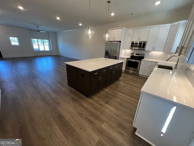 a living room with stainless steel appliances furniture and a kitchen view