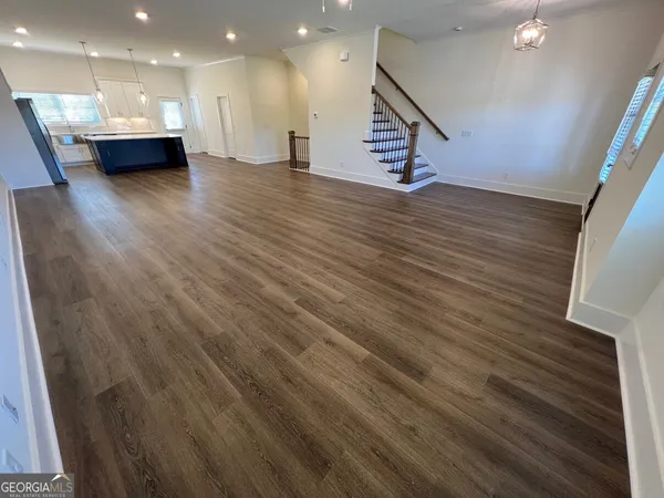 a view of an empty room with wooden floor and stairs
