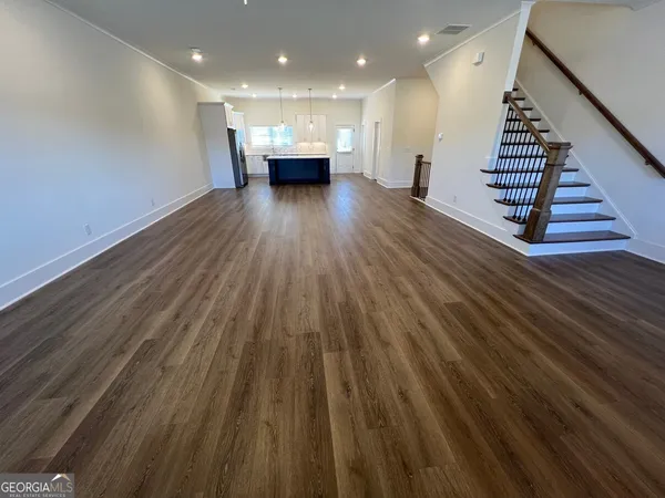 a view of an empty room with wooden floor and stairs