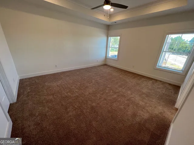 an empty room with windows and chandelier fan
