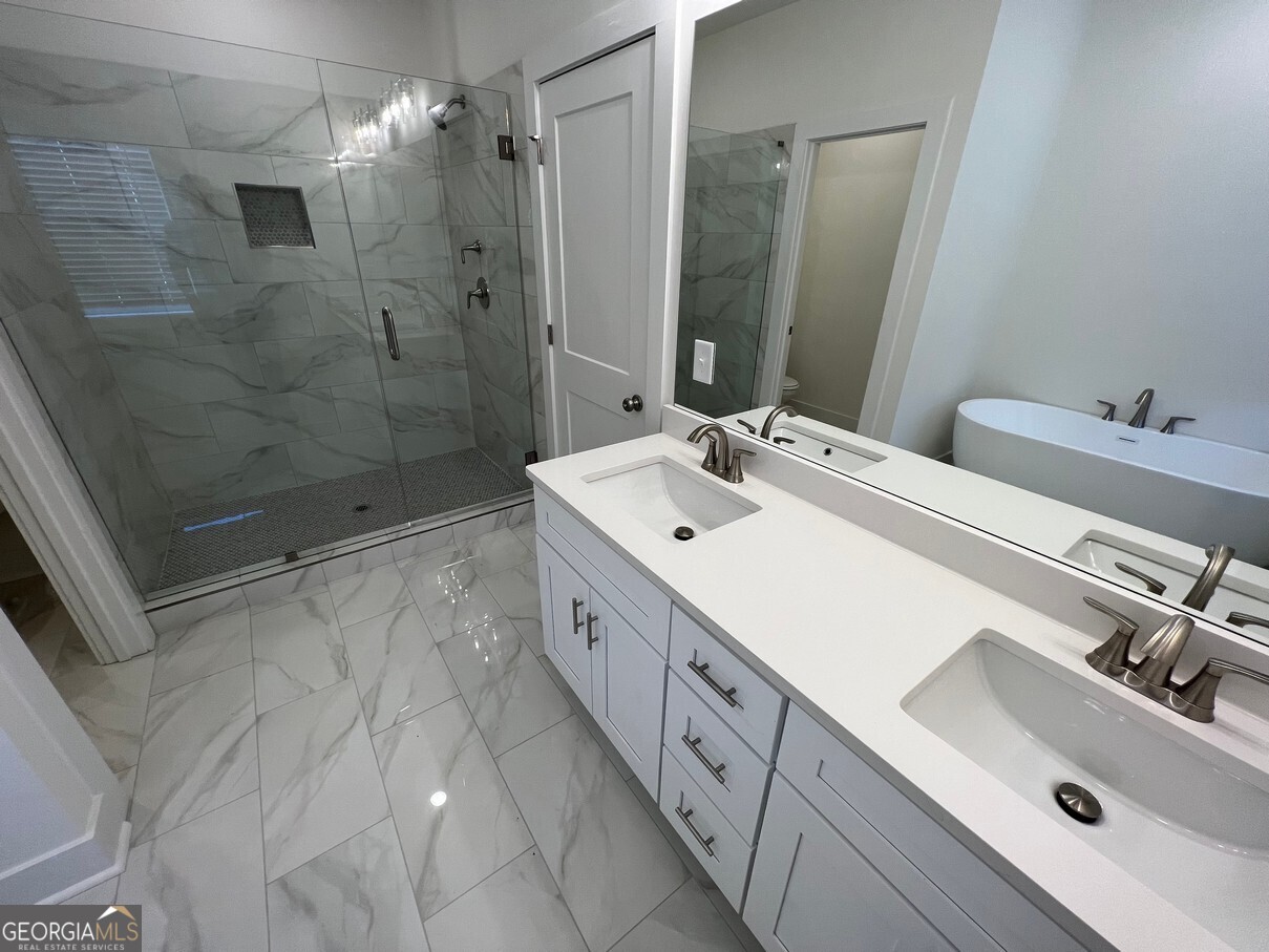 899 Duck Walk Way Lawrenceville, GA 30046 - Photo 28 of 49 a bathroom with a double vanity sink mirror double shower and a bathtub