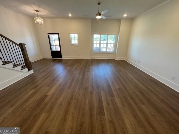 an empty room with wooden floor and windows