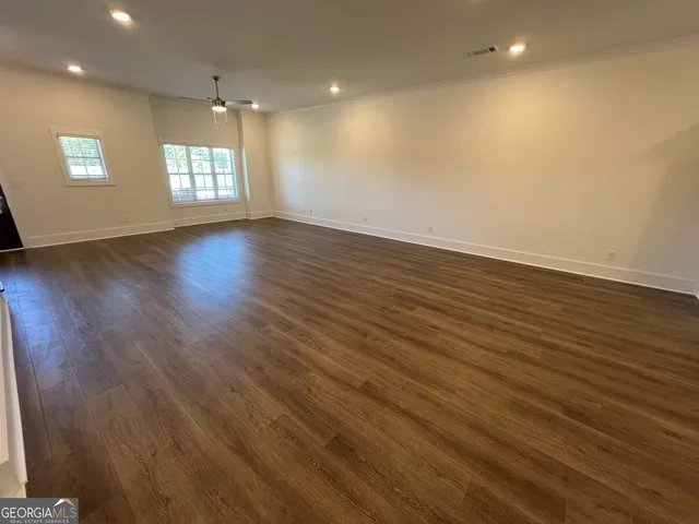 an empty room with wooden floor and windows