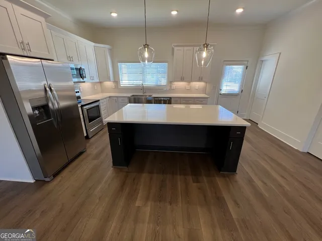 a kitchen with kitchen island wooden floors wooden cabinets a sink and appliances
