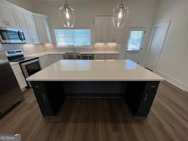 a large kitchen with a sink a stove wooden floor and cabinets