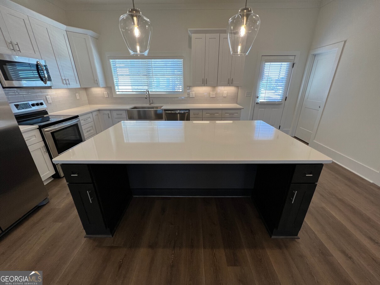 899 Duck Walk Way Lawrenceville, GA 30046 - Photo 9 of 49 a large kitchen with a sink a stove wooden floor and cabinets