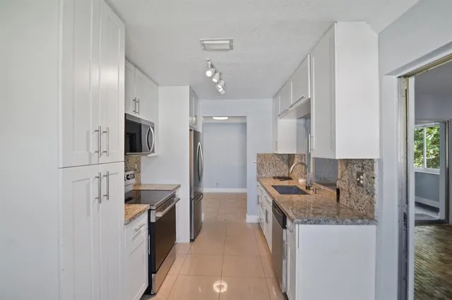 a kitchen with stainless steel appliances granite countertop a sink a stove and a refrigerator