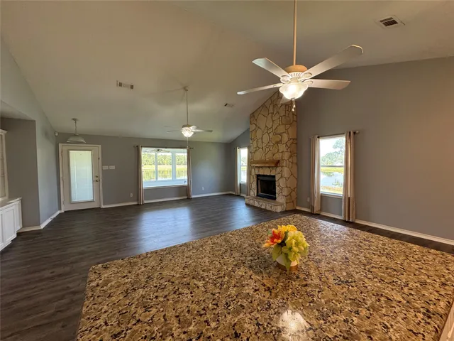 a view of a livingroom with a fireplace a ceiling fan and a window