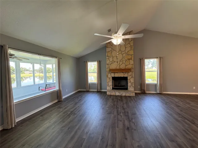 an empty room with wooden floor fireplace and windows