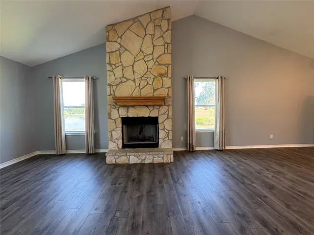 an empty room with wooden floor a fireplace and windows