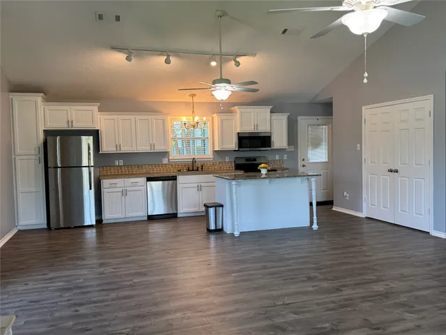 a kitchen with stainless steel appliances kitchen island granite countertop a stove a refrigerator and a microwave