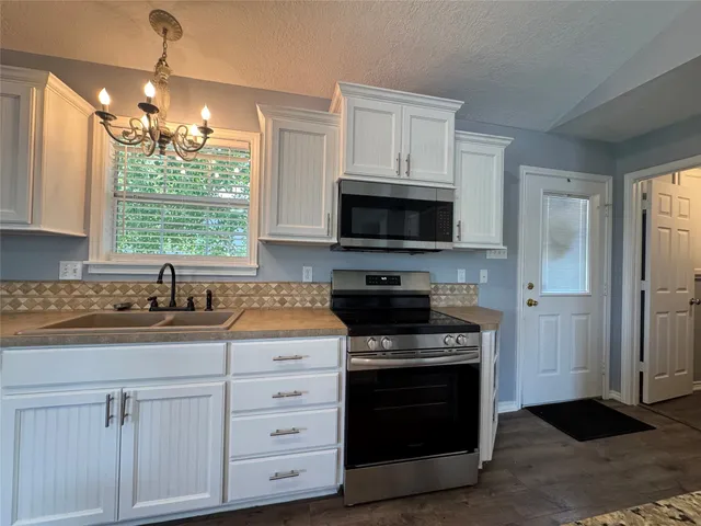 a kitchen with white cabinets stainless steel appliances and window