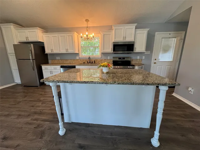 a kitchen with stainless steel appliances granite countertop a refrigerator a stove a sink and a microwave