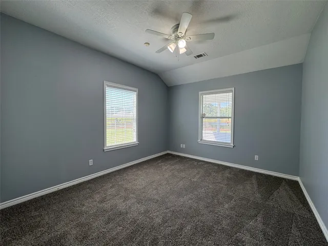 an empty room with windows and fan