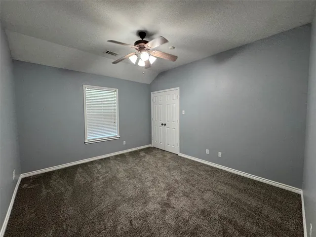 an empty room with windows and chandelier fan