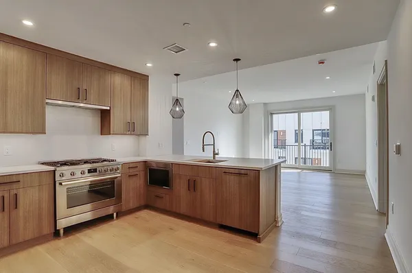 a large kitchen with a large counter top a sink stainless steel appliances and cabinets