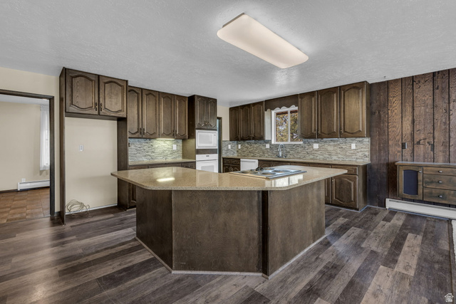 10705 Green Ridge Drive Sandy, UT 84070 - Photo 10 of 55 Kitchen featuring a center island, light stone counters, dark wood finish cabinets, dark wood-style flooring, and a textured ceiling