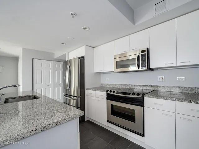 a kitchen with granite countertop stainless steel appliances and white cabinets