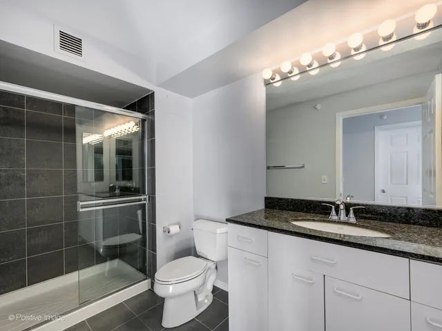 a bathroom with a granite countertop sink a toilet and a mirror