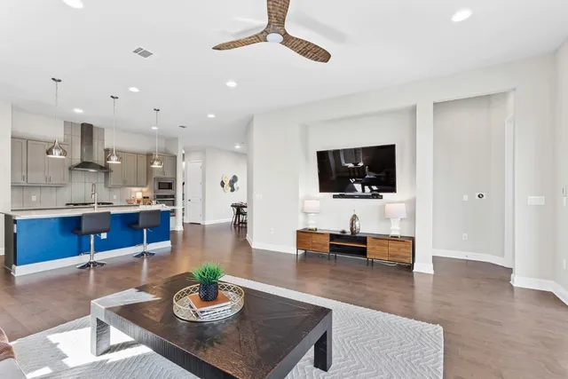 a living room with stainless steel appliances furniture and a flat screen tv