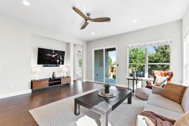 a living room with furniture floor to ceiling window hardwood floor and a flat screen tv