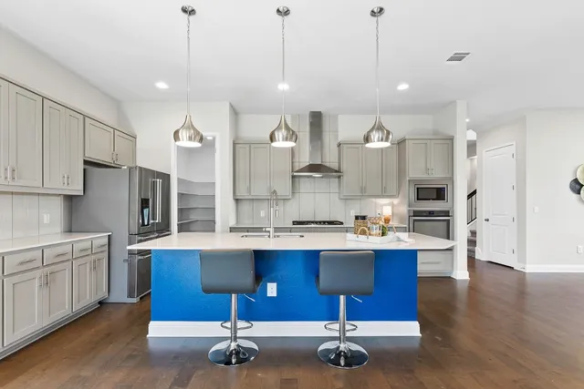 a kitchen with a sink a center island stainless steel appliances and cabinets
