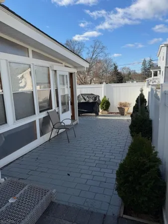 a view of a patio with couches and table and chairs with wooden floor and fence