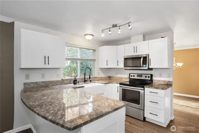 a kitchen with granite countertop a sink stainless steel appliances and cabinets