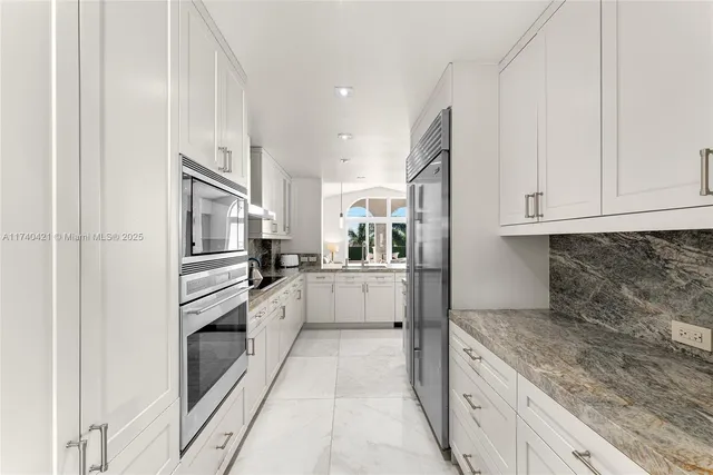 a large white kitchen with granite countertop a sink