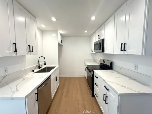 a kitchen with a sink cabinets and wooden floor