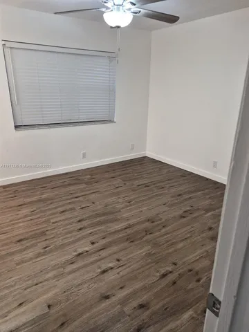 a view of a room with wooden floor and ceiling fan