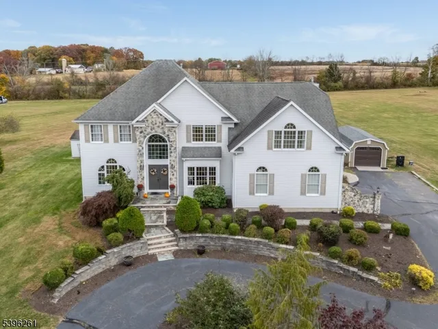 a view of a white house next to a yard with potted plants