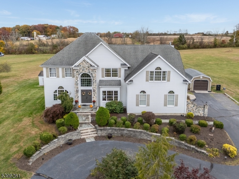 a view of a white house next to a yard with potted plants