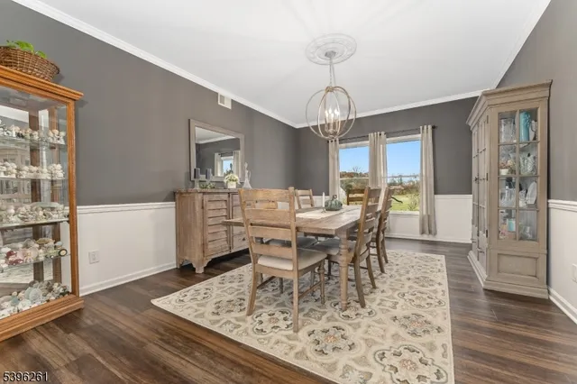 a kitchen with stainless steel appliances granite countertop a stove top oven a sink dishwasher white cabinets and a dining table with wooden floor