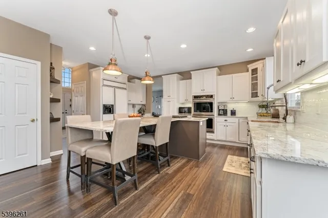 a kitchen with stainless steel appliances a dining table chairs stove and sink