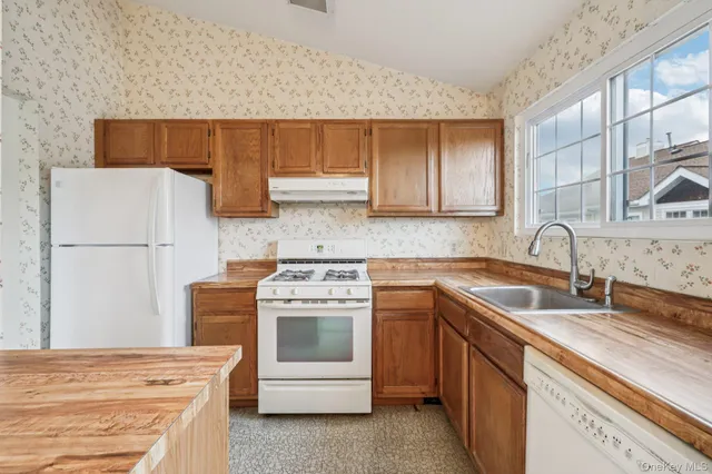 a utility room with stainless steel appliances granite countertop a stove and a sink