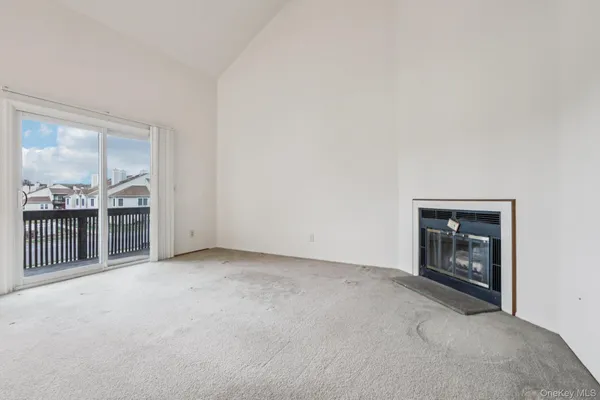 a view of an empty room with a fireplace and window