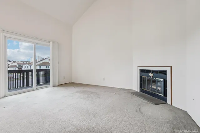 a view of an empty room with a fireplace and window