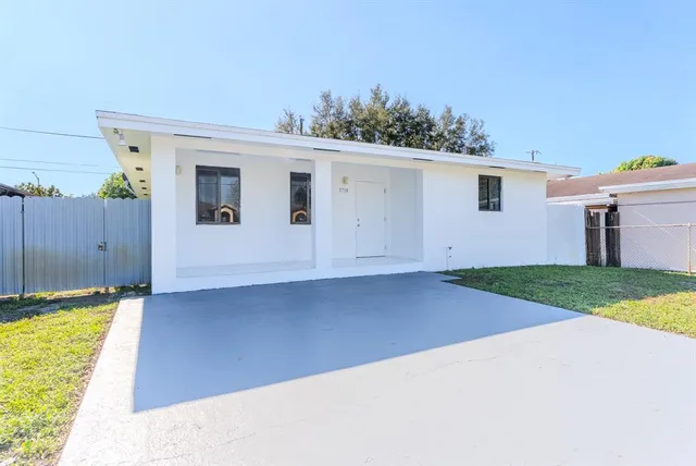 a view of a house with backyard and wooden fence