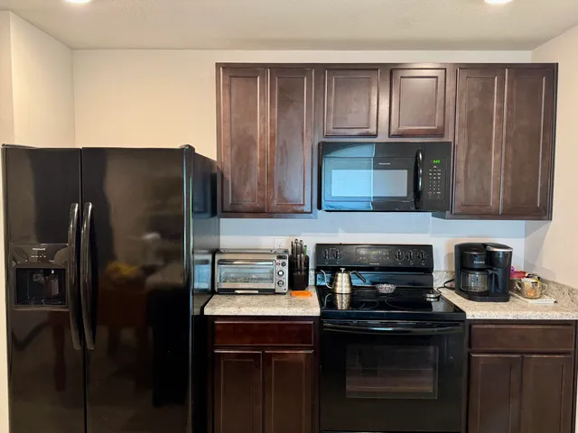 a kitchen with granite countertop wooden cabinets and a stove top oven