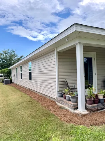 a backyard of a house with table and chairs and potted plants