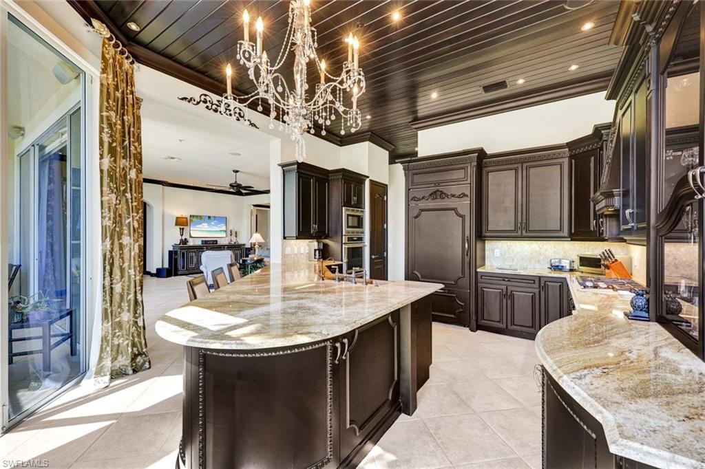 15516 Monterosso Lane, Unit 101 Naples, FL 34110 - Photo 12 of 31 Kitchen featuring dark wood finish cabinetry, ornamental molding, light stone counters, backsplash, and a ceiling fan