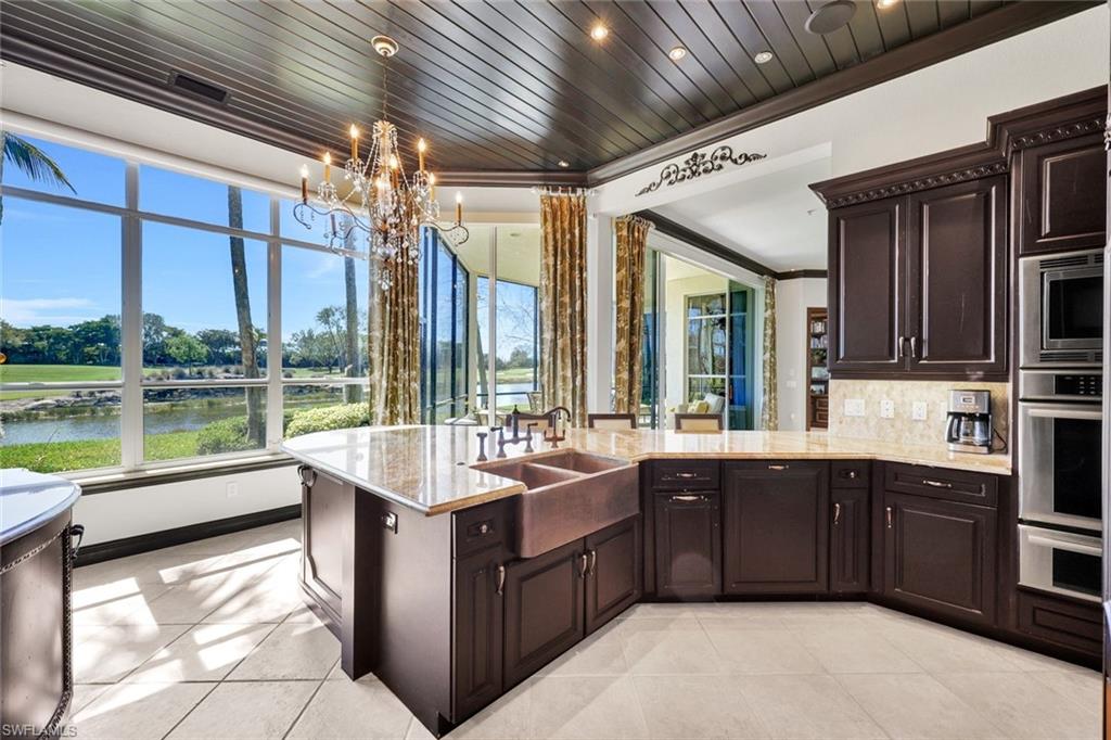 15516 Monterosso Lane, Unit 101 Naples, FL 34110 - Photo 14 of 31 Kitchen featuring dark wood finish cabinetry, stainless steel appliances, a peninsula, plenty of natural light, and crown molding